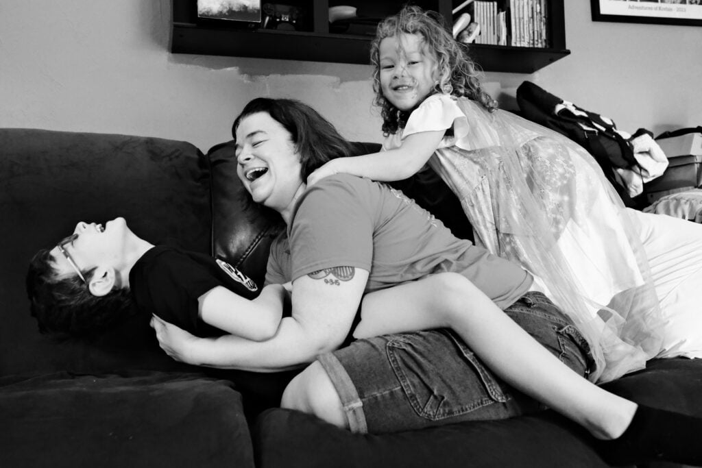 Mother embracing her son while her daughter joins them on the couch
