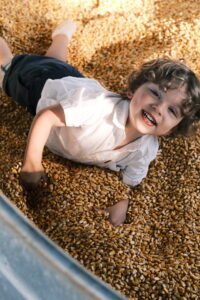 Toddler is smiling while playfully laying in corn